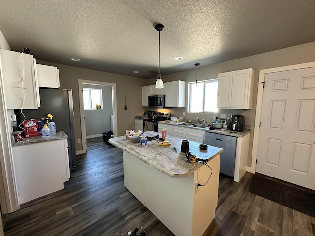 kitchen with a kitchen island, dark wood finished floors, appliances with stainless steel finishes, white cabinets, and a sink