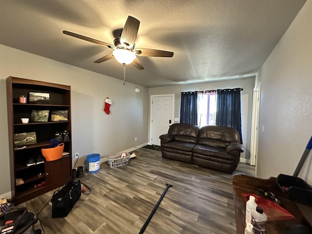 living area featuring a ceiling fan, wood finished floors, baseboards, and a textured ceiling