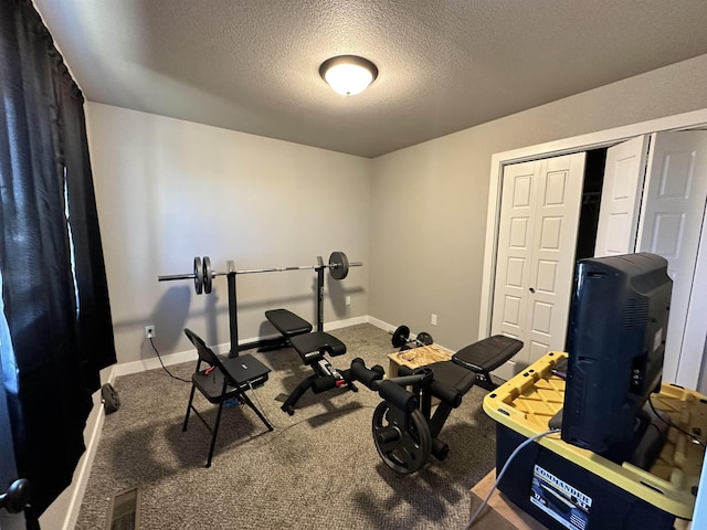 workout area featuring visible vents, carpet, baseboards, and a textured ceiling