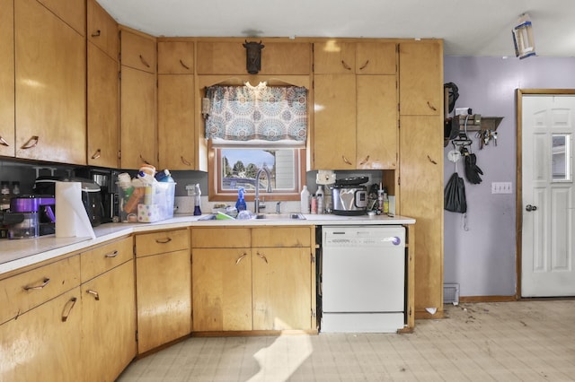 kitchen featuring a sink, light countertops, baseboards, and white dishwasher