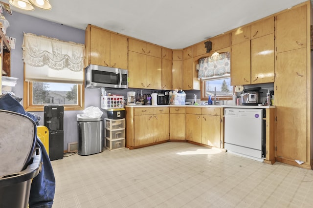 kitchen with stainless steel microwave, light floors, white dishwasher, and light countertops