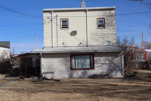 back of house featuring a lawn and metal roof