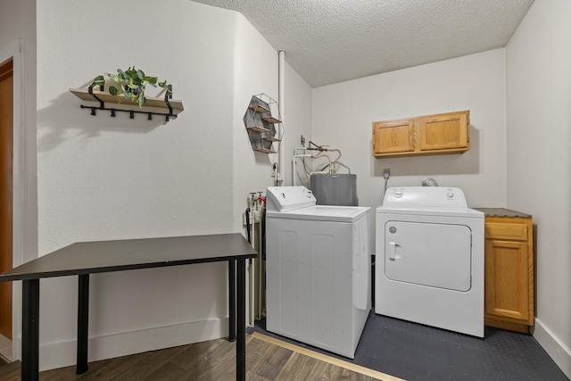 washroom featuring dark wood-style flooring, a textured ceiling, cabinet space, water heater, and washing machine and dryer