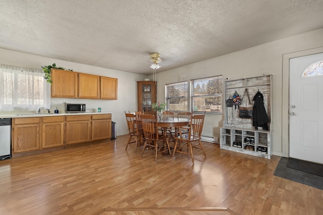 dining room with light wood-style floors, a baseboard heating unit, and a textured ceiling