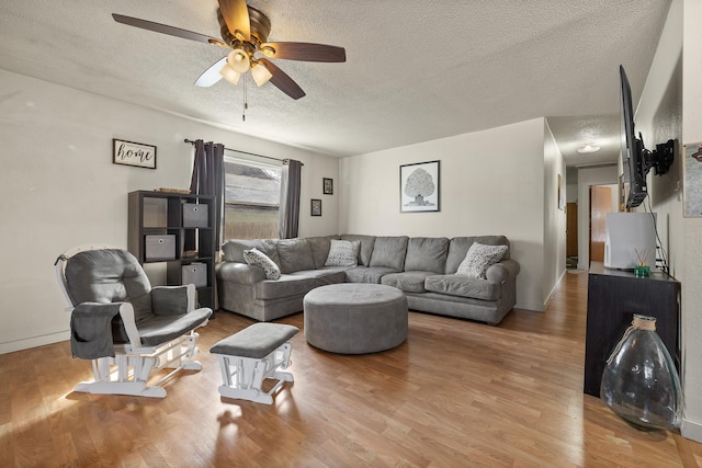 living room with a textured ceiling, wood finished floors, baseboards, and a ceiling fan