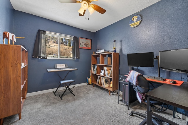 carpeted home office with baseboards, ceiling fan, and a textured wall