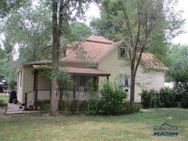 23508 Main St, Caputa, SD 57725 - view of front of house featuring covered porch, a front yard, and roof with shingles