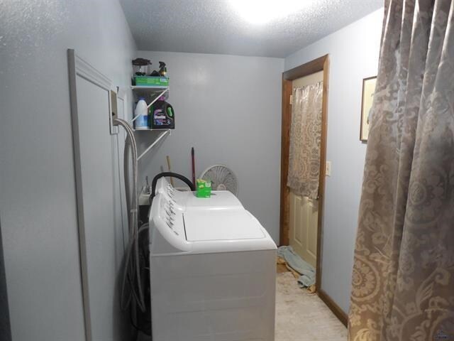 23508 Main St, Caputa, SD 57725 - laundry room featuring washing machine and clothes dryer, laundry area, and a textured ceiling