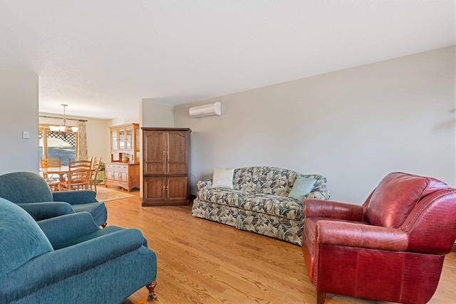 living room featuring light wood-style floors, an AC wall unit, and a notable chandelier