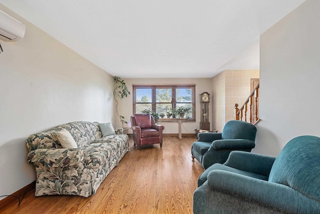 living room with baseboards, an AC wall unit, stairway, and wood finished floors
