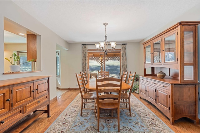 dining room featuring a textured ceiling, a notable chandelier, and light wood finished floors