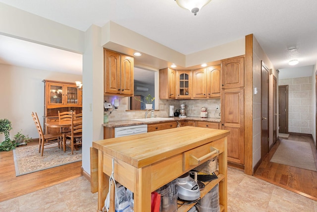 kitchen featuring a sink, tasteful backsplash, glass insert cabinets, butcher block counters, and white dishwasher