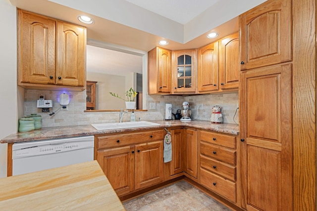 kitchen with decorative backsplash, glass insert cabinets, a sink, and dishwasher