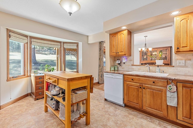 kitchen featuring light countertops, an inviting chandelier, decorative backsplash, a sink, and dishwasher