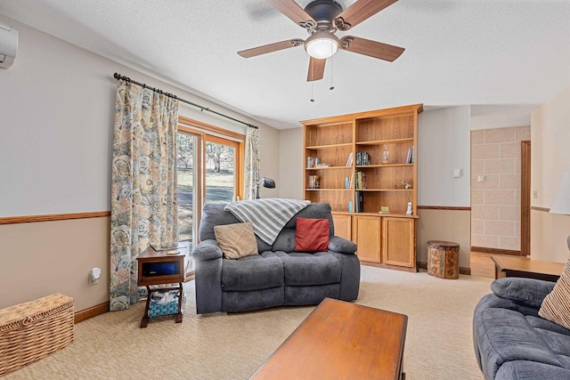 living room featuring light colored carpet, baseboards, a textured ceiling, a ceiling fan, and a wall mounted air conditioner
