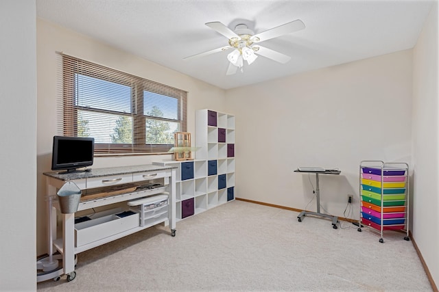 carpeted office space with baseboards and a ceiling fan