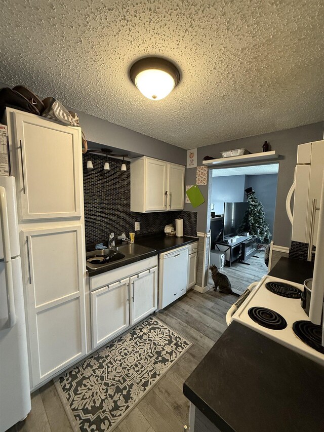 4809 Meadow Dr, Black Hawk, SD 57718 - kitchen with white cabinets, wood finished floors, dark countertops, and white appliances