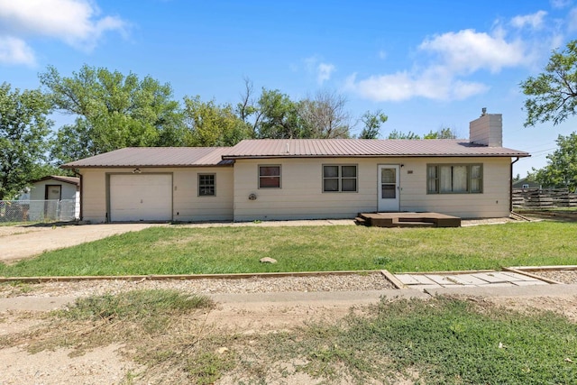 view of front of house with driveway, a chimney, fence, metal roof, and a garage