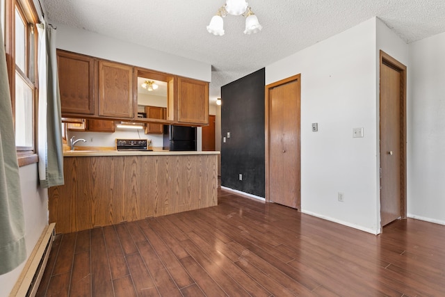 kitchen featuring range, a peninsula, baseboard heating, dark wood-type flooring, and freestanding refrigerator