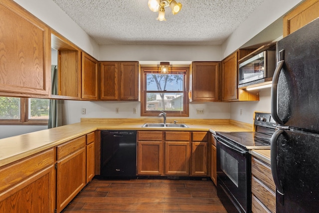 kitchen with light countertops, a sink, black appliances, and dark wood finished floors