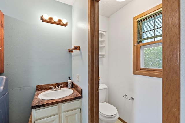bathroom with a textured ceiling, toilet, and vanity