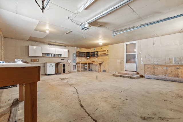 garage featuring electric panel, a garage door opener, and a workshop area