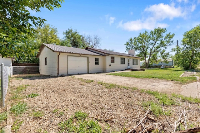 view of front of home with metal roof, fence, a chimney, a garage, and a front yard