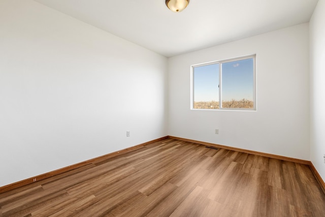 spare room with baseboards, light wood finished floors, and visible vents