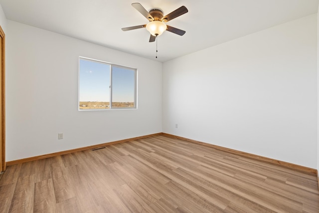 empty room featuring baseboards, ceiling fan, visible vents, and light wood-style floors