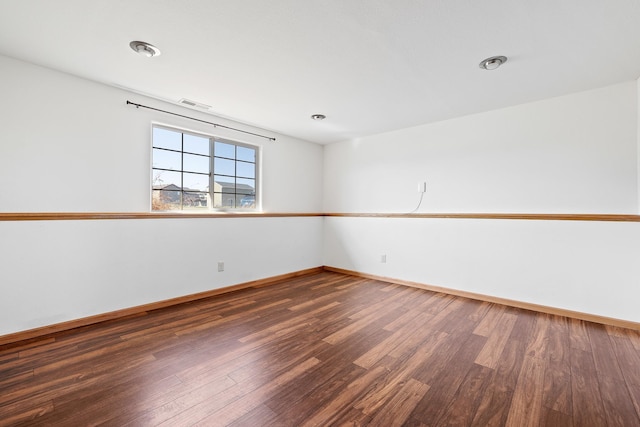 empty room with baseboards, visible vents, and wood finished floors