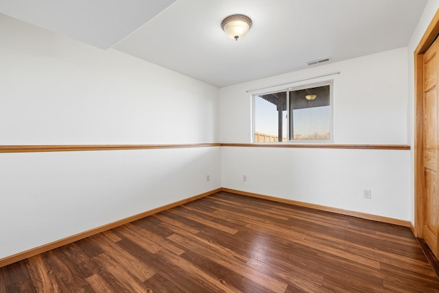 empty room with baseboards, visible vents, and dark wood-style flooring