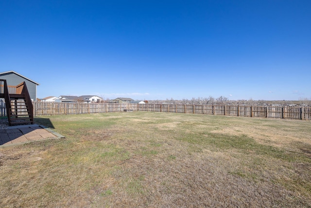 view of yard featuring a fenced backyard and stairs