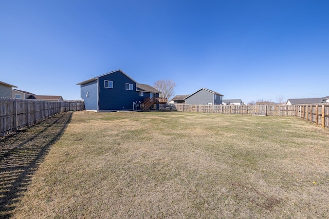 view of yard with a fenced backyard and stairs