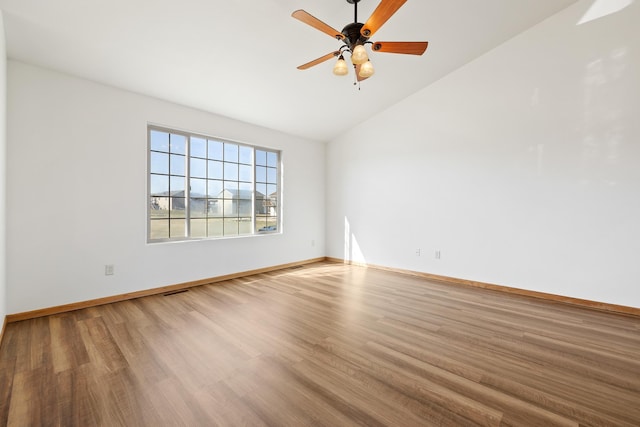 empty room with lofted ceiling, baseboards, visible vents, ceiling fan, and wood finished floors