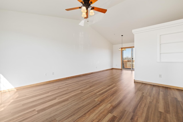 empty room featuring ceiling fan with notable chandelier, baseboards, vaulted ceiling, and wood finished floors