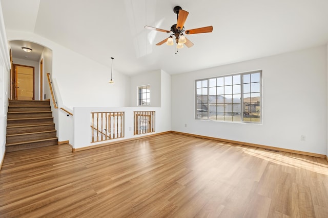 spare room with wood finished floors, lofted ceiling, baseboards, arched walkways, and ceiling fan