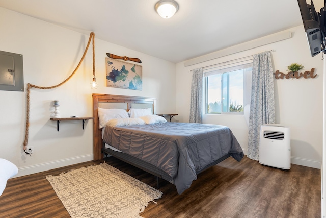 bedroom with electric panel, baseboards, and wood finished floors