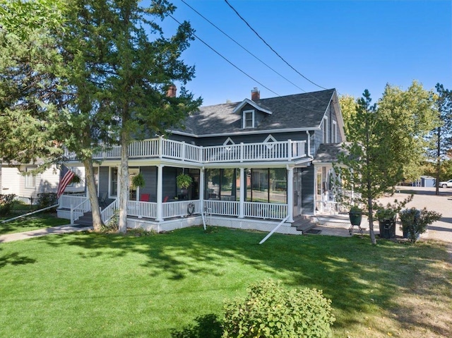 back of property featuring a porch, a balcony, a chimney, and a lawn