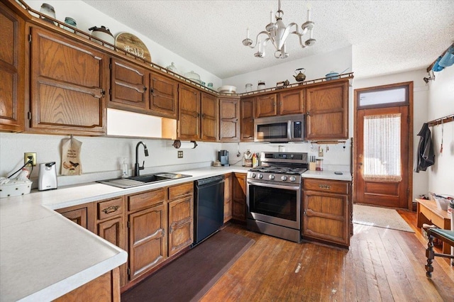 kitchen featuring appliances with stainless steel finishes, light countertops, brown cabinetry, dark wood finished floors, and a sink