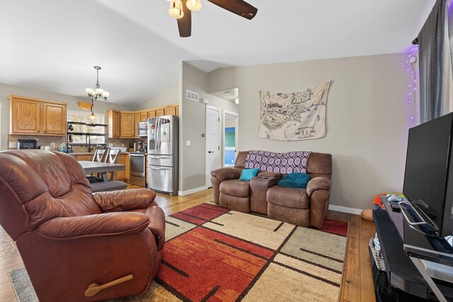 1914 7th Ave, Belle Fourche, SD 57717 - living area featuring ceiling fan with notable chandelier, visible vents, lofted ceiling, light wood finished floors, and baseboards