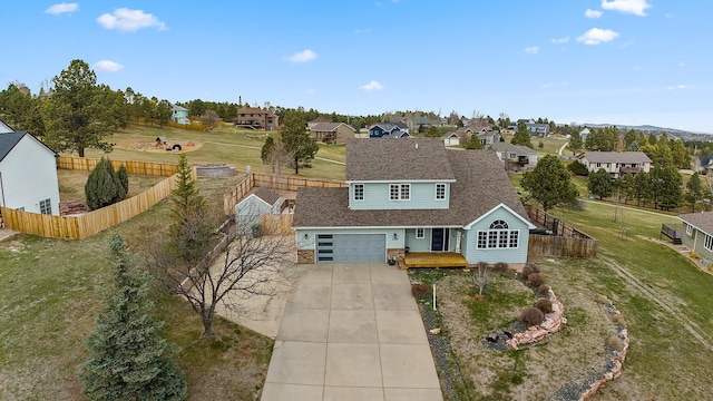 traditional-style house with concrete driveway, a front lawn, a residential view, and a fenced backyard