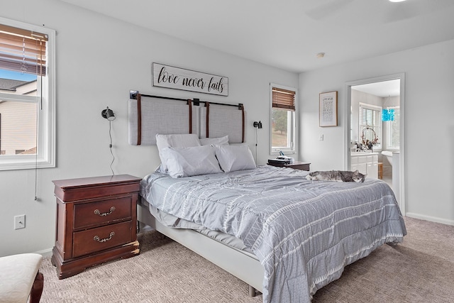 carpeted bedroom featuring ensuite bath and baseboards