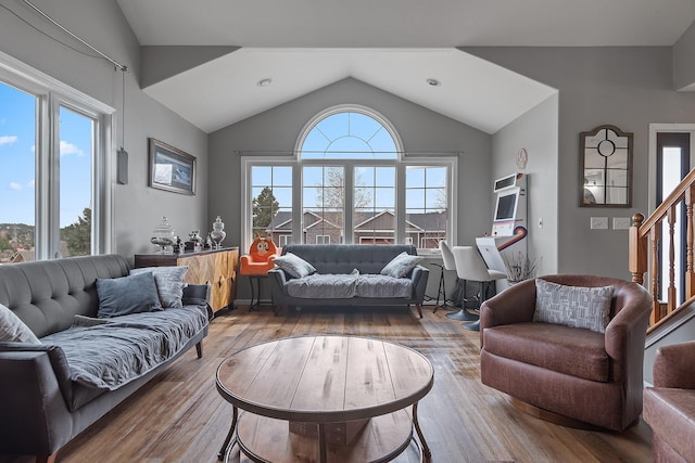 living area with lofted ceiling, wood finished floors, and stairway