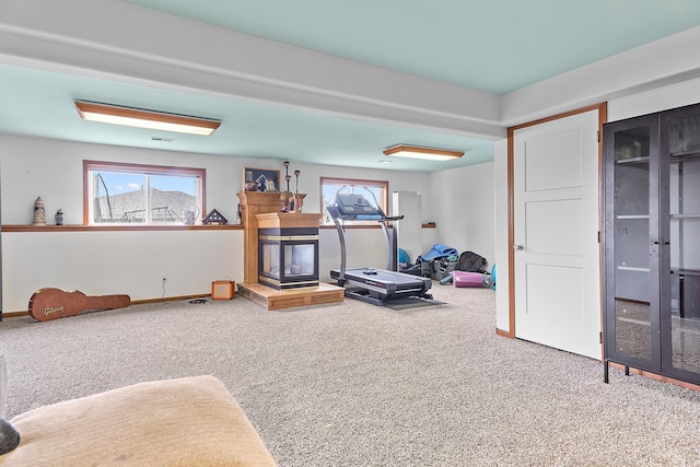 workout room with baseboards, carpet, and a multi sided fireplace