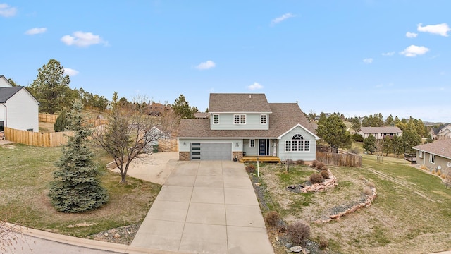 traditional-style home featuring fence, driveway, and a front yard