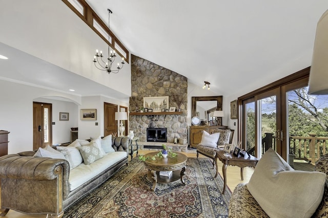 living room featuring a stone fireplace, a chandelier, crown molding, light wood-style floors, and arched walkways