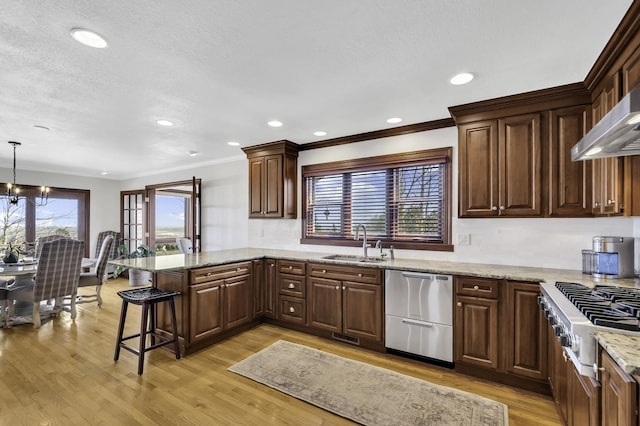 kitchen featuring light wood-style floors, a peninsula, a breakfast bar, a sink, and stainless steel appliances
