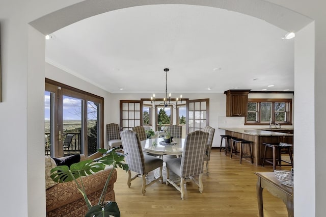 dining room with crown molding, baseboards, light wood-type flooring, and a chandelier