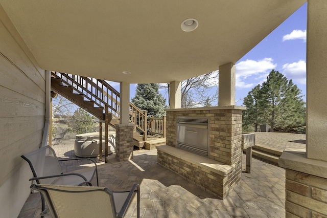 view of patio featuring central AC unit, an outdoor brick fireplace, and stairs