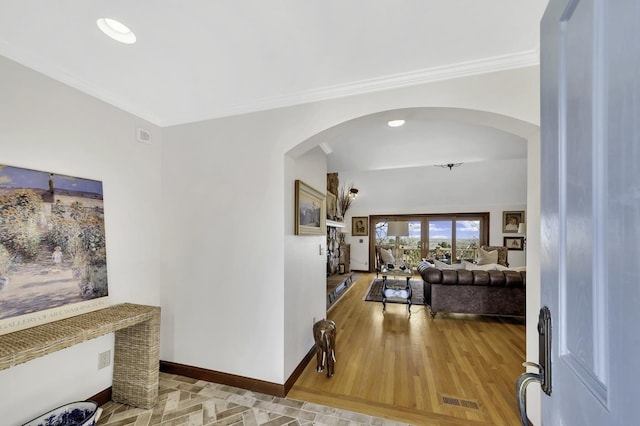 entryway featuring visible vents, baseboards, arched walkways, ornamental molding, and wood finished floors